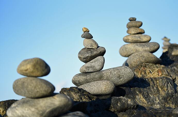 Three piles of balancing rocks against blue sky